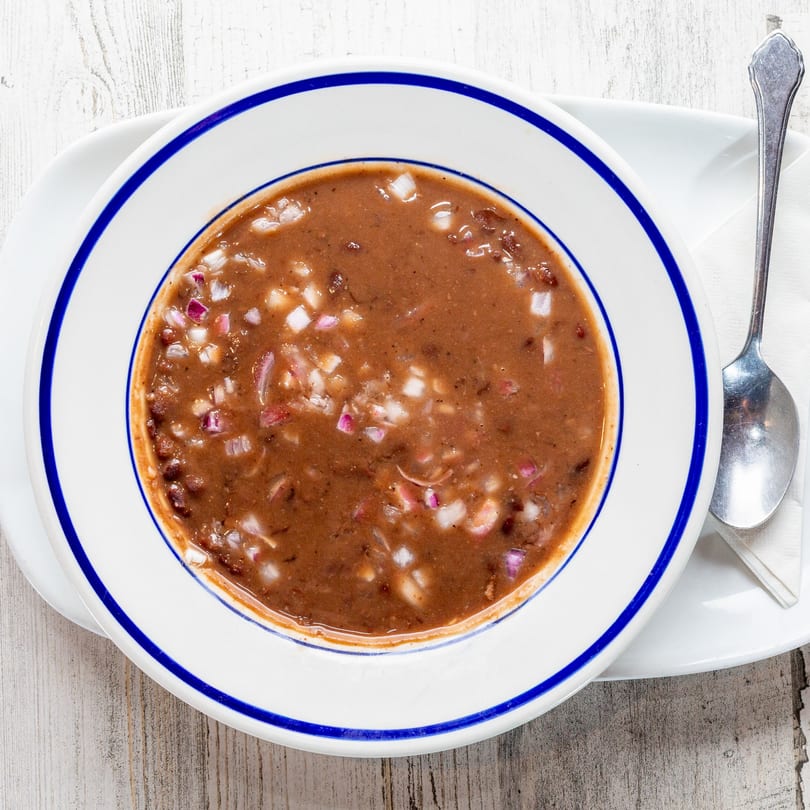 A bowl of White Wolf Cafe's black bean soup, topped with diced red and white onions.